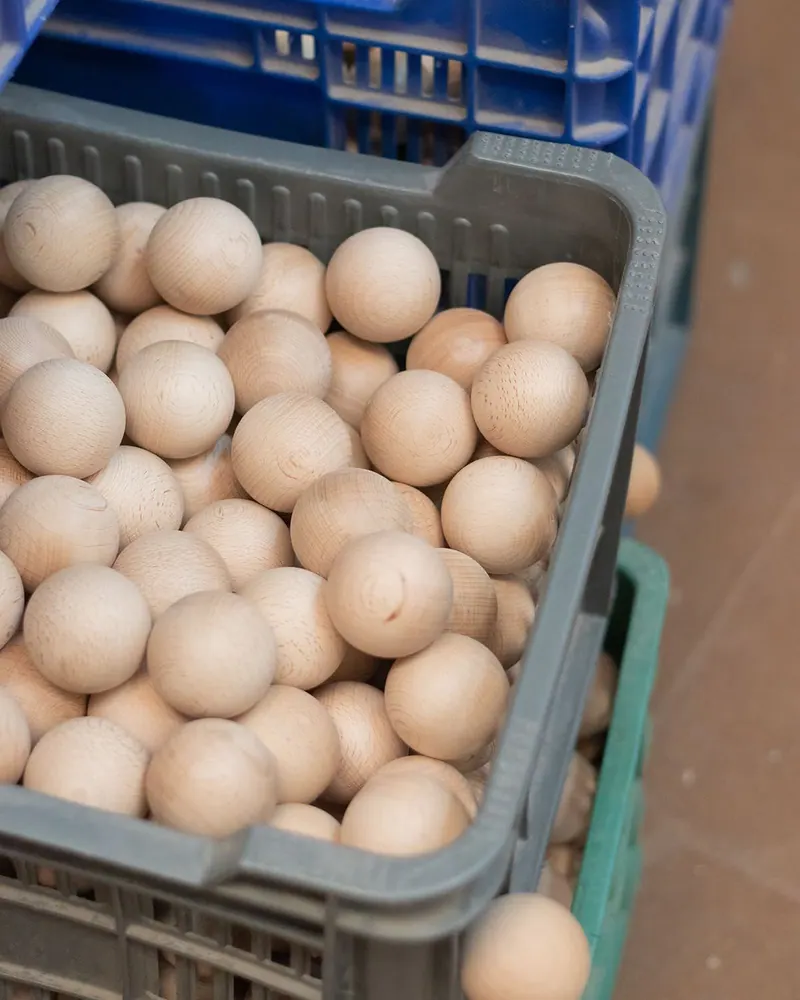 Cesta llena de bolas de madera de haya en crudo
