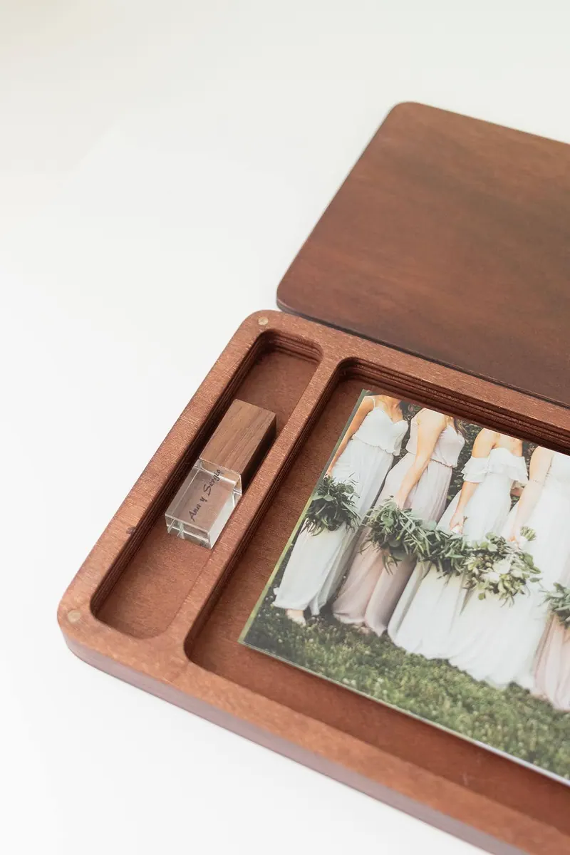 Caja de nogal abierta con fotos de boda y pendrive de madera